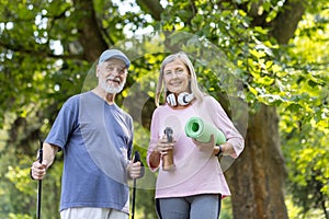 Portrait of a scary couple, gray-collared man and woman doing sports in the park, standing with trekking poles, holding