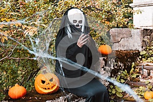 Portrait of scary woman with skeleton makeup and carved pumpkin.