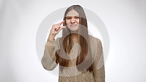 Portrait of sceptic girl showing small size with hand over white studio background