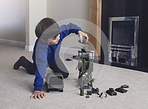 Portrait of School boy sitting on carpet floor playing with soldiers, military car and figurine toys, Happy Kid playing wars and