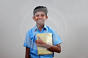 A school boy wearing uniform holds note books in hand photo