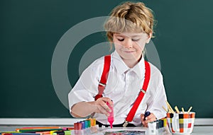 Portrait school kid boy doing art homework, holding pencil, writing. Child boy drawing on elementary school. Kids art