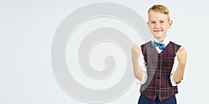 A portrait of a schoolboy who clenches his hands into a fist affirmatively, making a gesture. Isolated background