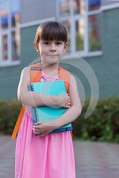 Portrait of schoolgirl child with backpack and books isolated on a school background