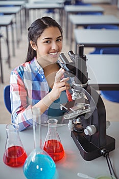 Portrait of schoolgirl experimenting on microscope in laboratory