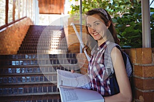 Portrait of schoolgirl reading book near staircase