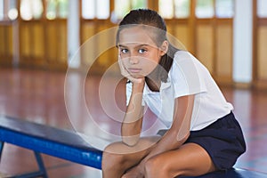 Portrait of schoolgirl sitting in basketball court