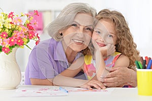 Portrait of schoolgirl studying with grandmother at home