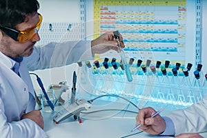 Portrait of a scientist working in the lab examines a test tube with liquid.