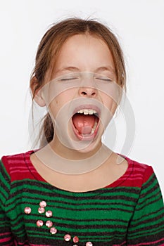 Portrait of a screaming 8-year-old girl in a sweater in crimson and green stripes