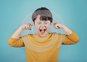 portrait of a Screaming little boy covering ears with hands