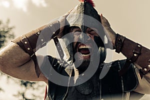 Portrait of screaming in rage ancient Spartan warrior in helmet