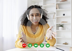 Portrait screen view of happy young black woman in headphones making video call, using computer from home