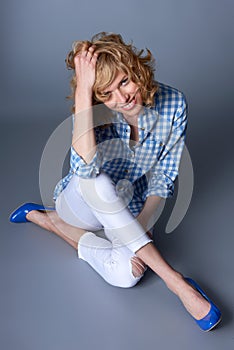 Portrait of seated casual young blond fashion model in blue