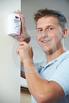 Portrait Of Security Consultant Fitting Burglar Alarm Sensor In