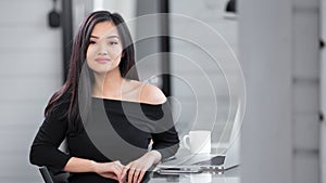 Portrait seductive Asian fashion girl wearing black dress sitting at working table