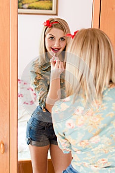 Portrait of seductive young blonde beautiful woman having fun posing draws in the mirror red lipstick lips