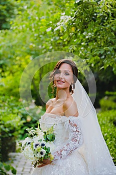 Portrait of seductive young bride at the background of green summer garden