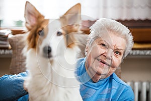 portrait of a senior adult woman holding a half breed dog on her lap