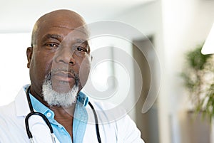 Portrait of senior african american male doctor in hospital corridor, with copy space