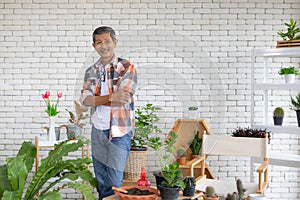 A portrait of a senior Asian man gardener poses with happy in planting corner at home