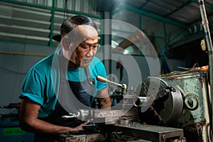 Portrait of Senior Asian man is a mechanic who owns a family business lathe. A small industrial lathe is being installed and
