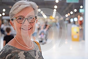 Portrait of senior attractive woman enjoying shopping in a mall, smiling looking at camera. Happy gray haired people