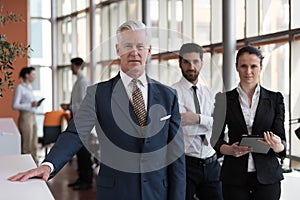 Portrait of senior businessman as leader with group of people i