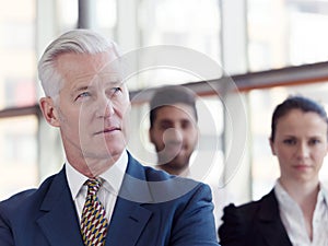 Portrait of senior businessman as leader with staff in backgrou