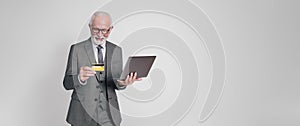 Portrait of senior businessman with laptop and credit card doing online shopping on white background
