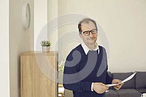 Portrait of a senior businessman standing with documents in his hands and looking at the camera.