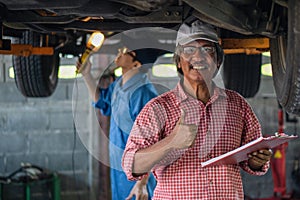 Portrait of senior car mechanic checking car for maintenace program in garage and car maintenance service station
