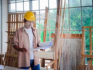 Portrait of a senior carpenter looking at blueprints plans, rechecking and comparing drawing plans. Hobby, Retirement Concept