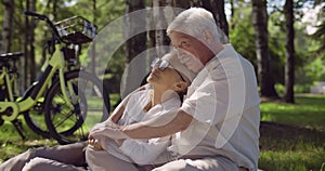 Portrait of senior caucasian couple sitting in park together and hugging
