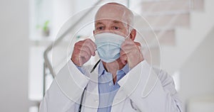 Portrait of senior caucasian male doctor wearing face mask looking at camera