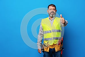 Portrait of senior construction worker in yellow vest in studio