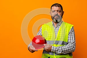 Portrait of senior construction worker in yellow vest in studio