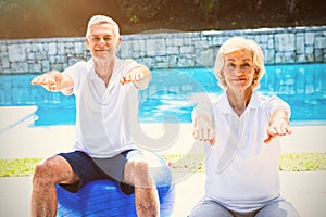 Portrait of senior couple doing aerobics at poolside