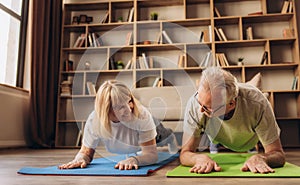 Portrait of a Senior Couple Doing Gymnastics and Yoga Stretching Exercises Together at Home on Sunny Morning. Concept of