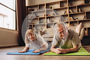 Portrait of a Senior Couple Doing Gymnastics and Yoga Stretching Exercises Together at Home on Sunny Morning. Concept of