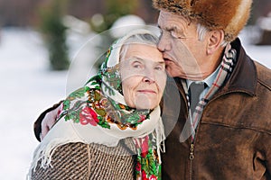 Portrait of senior couple. Elderly man kiss his wife in weighty. old couple walking in the park in winter time. Happy