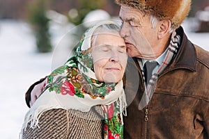 Portrait of senior couple. Elderly man kiss his wife in weighty. old couple walking in the park in winter time. Happy