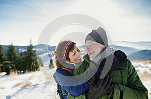 Portrait of senior couple hikers standing in snow-covered winter nature.