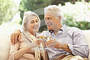 Portrait Of Senior Couple Relaxing On Sofa With Glass Of Wine