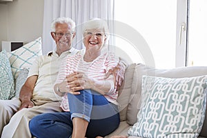 Portrait Of Senior Couple Relaxing On Sofa At Home Together