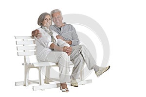 Portrait of senior couple sitting on bench on white background