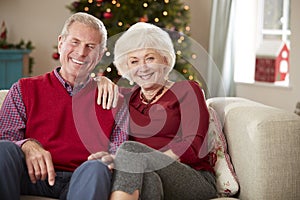 Portrait Of Senior Couple Sitting On Sofa In Lounge At Home On Christmas Day