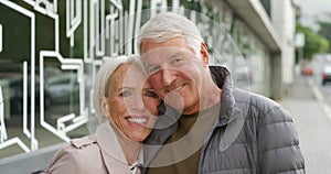 Portrait of a senior couple smiling outside in an urban city. Stylish mature, retired married husband and wife bonding