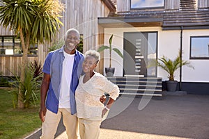 Portrait Of Senior Couple Standing In Driveway In Front Of Dream Home Together