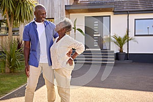 Portrait Of Senior Couple Standing In Driveway In Front Of Dream Home Together
